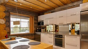 A modern kitchen with wooden beams, white cabinets, stainless steel appliances, and a large window.