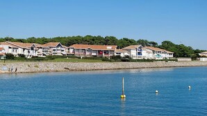 Une rangée de charmantes maisons de vacances en bord de mer, offrant une vue dégagée sur l’océan et un littoral rocheux.