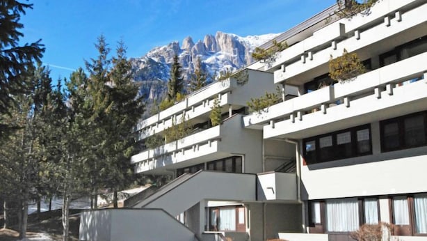 A modern building with multiple balconies, surrounded by snow and trees, with a mountain in the background. - Solaria by Interhome (Canazei)