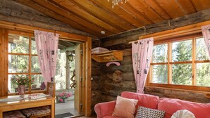 A cozy cabin interior with a wooden ceiling, a pink sofa, and a dining area with a table and chairs. - Rinnekämppä by Interhome (Asikkala)
