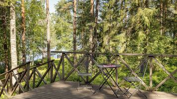 A wooden deck with metal chairs and a table, surrounded by tall trees.