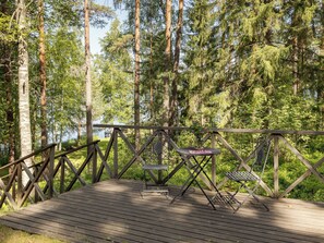 A wooden deck with metal chairs and a table, surrounded by tall trees. - Rinnekämppä by Interhome (Asikkala)