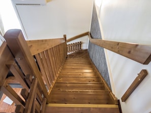 Un escalier en bois, doté d’une rampe et d’une main courante en bois, situé du côté droit.