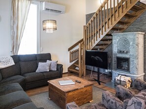 A living room with a sofa, a coffee table, a TV, a fireplace, and a staircase.