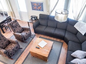 A living room with a sofa, two patterned armchairs, a wooden coffee table, and a remote control.