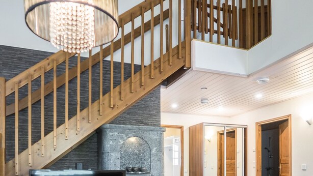 A modern interior with a wooden staircase, a fireplace, and a cozy seating area.