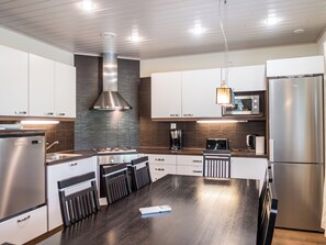 A modern kitchen with stainless steel appliances, a central island, and a built-in stove.