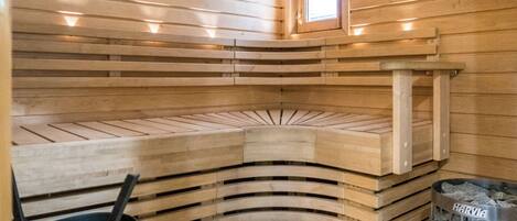 Una sauna amb seients de fusta, una finestra i un escalfador de sauna Harvia.