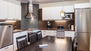 A modern kitchen with stainless steel appliances, a central island with seating, and a built-in microwave.