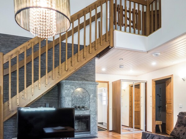 A modern interior with a wooden staircase, a fireplace, and a sofa.