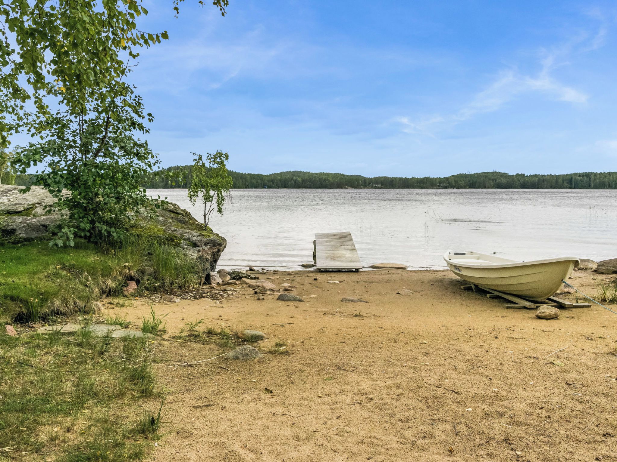 A sandy beach with a wooden dock and a boat.