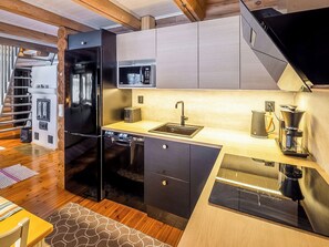 Een kleine keuken met een ingebouwde magnetron, een spoelbak en een koffiezetapparaat.
