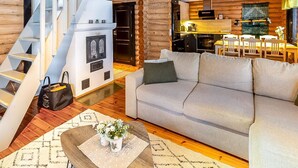 A modern log cabin interior with a staircase, a sofa, a dining area, and a kitchen. - Vacation home Tiira by Interhome (Puumala)