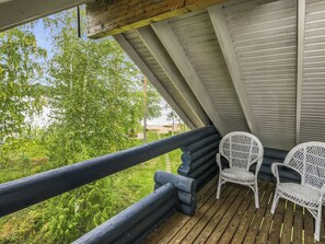A wooden deck with two wicker chairs, a railing, and a view of greenery. - Vacation home Tiira by Interhome (Puumala)