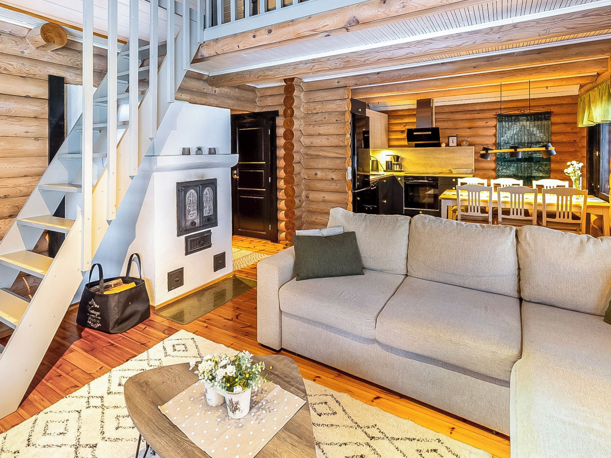 Een modern interieur met een trap, een bank, een eethoek en een keuken.