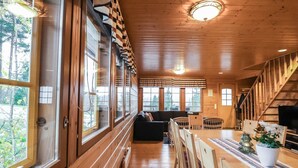 A wooden cabin interior with a dining area, sofa, and staircase. - Dominus by Interhome (Raasepori)