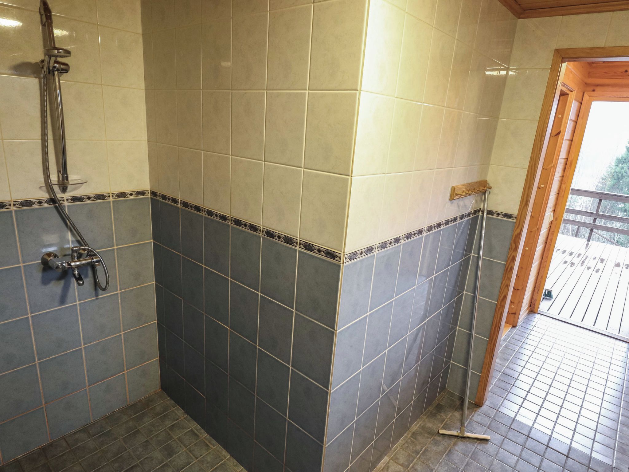 Une salle de bain avec une douche, des murs carrelés et une porte en bois.