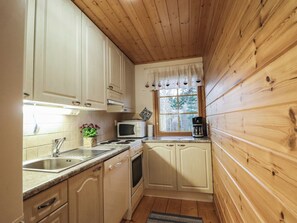 Une cuisine de taille réduite avec des murs en bois, une fenêtre et des appareils électroménagers de base.