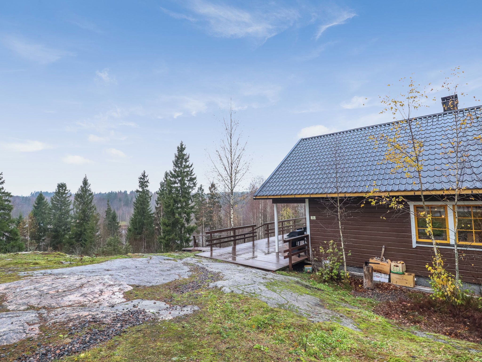 Une cabane au revêtement extérieur en bois, un sentier de pierres menant à celle-ci, et un paysage boisé en arrière-plan.