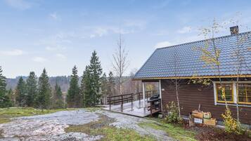 Une cabane au revêtement extérieur en bois, un sentier de pierres menant à celle-ci, et un paysage boisé en arrière-plan.