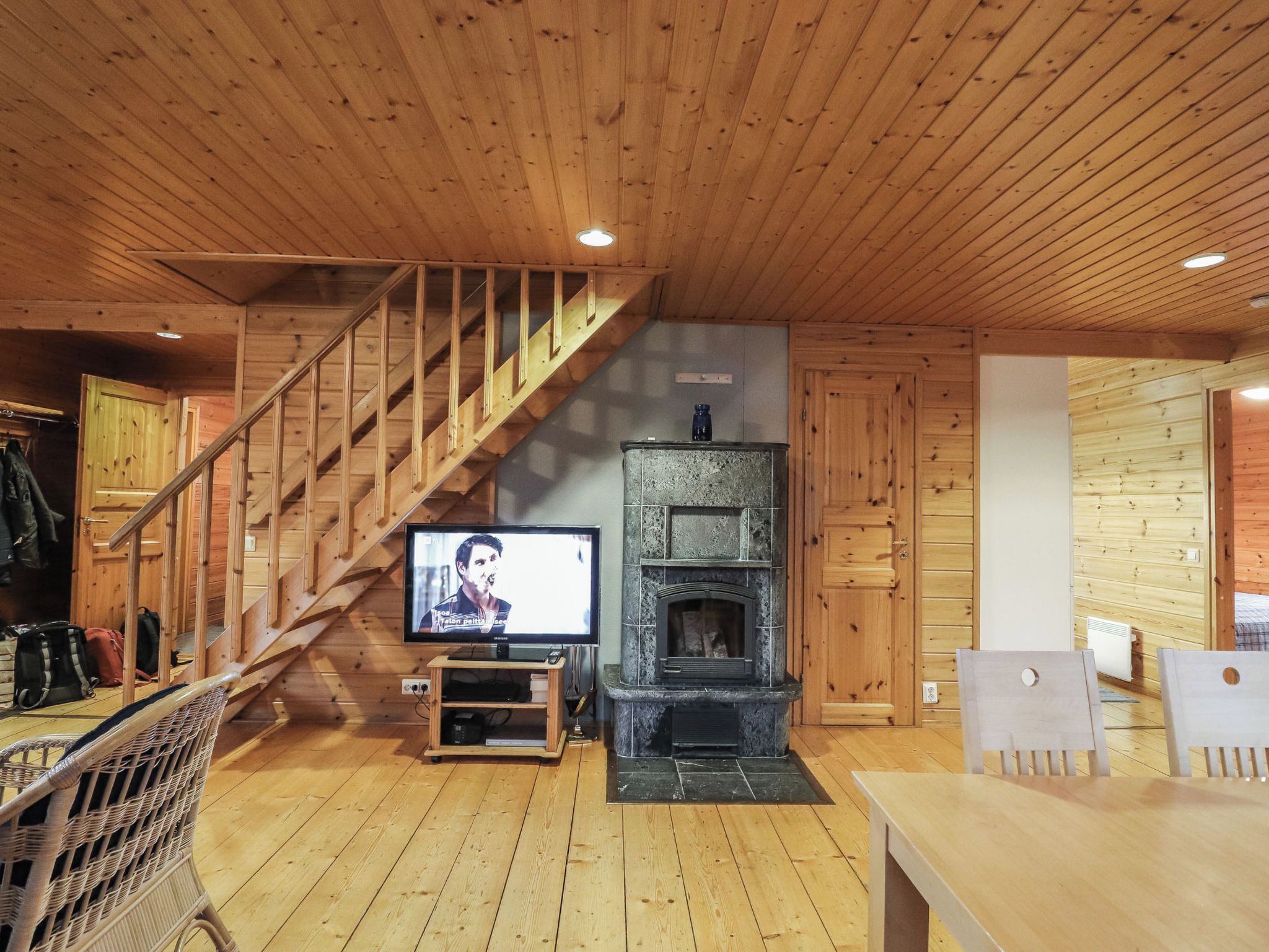 A wooden interior with a staircase, a television, a fireplace, and a dining area.
