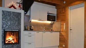 A modern kitchen with a built-in microwave, white cabinets, and a fireplace. - Rantamökki by Interhome (Luhanka)