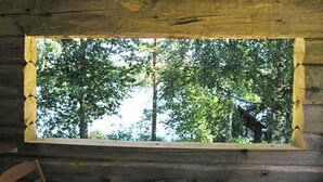 A rustic cabin interior with a large window overlooking a forested area. - Rantamökki by Interhome (Luhanka)