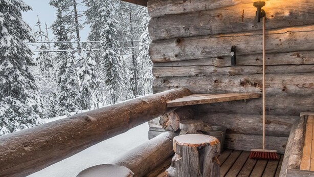 Une terrasse en bois avec un banc rustique et un balai appuyé contre le mur.