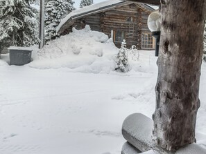 Paisaje nevado con una cabaña de madera y un gran montículo de nieve.