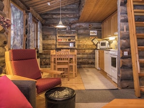 Un intérieur chaleureux de chalet en bois, avec un coin repas, des meubles en bois et une petite cuisine.