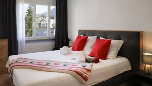 A neatly made bed with a white bedspread, red and white pillows, and a decorative blanket. - Allod Park Haus C 301 by Interhome (Davos)