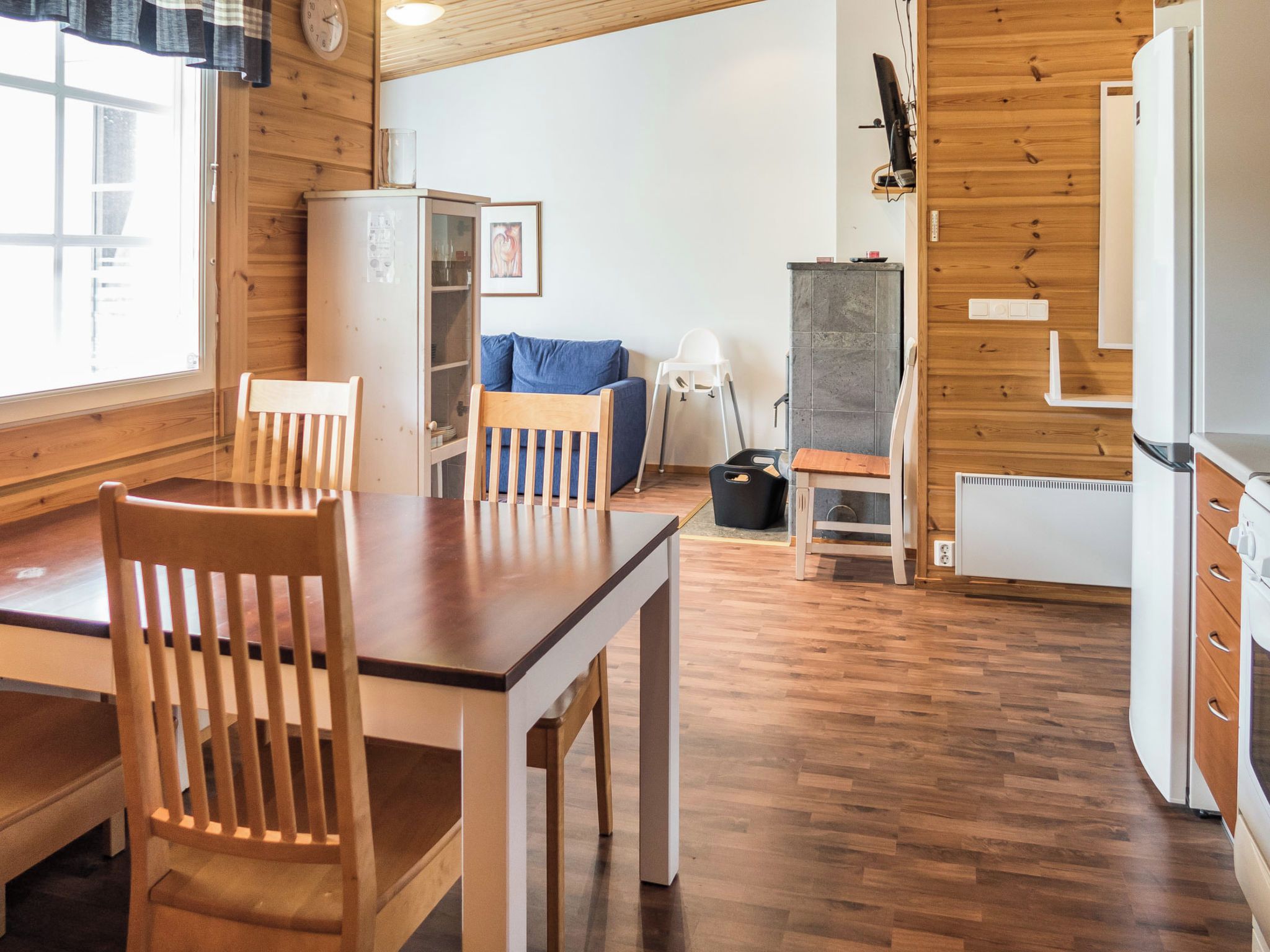 Un intérieur en bois comprenant une table à manger, des chaises, un réfrigérateur, une cuisinière et une fenêtre.
