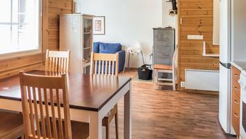 Un interior de madera con una mesa de comedor, sillas, un refrigerador, una estufa y una ventana.