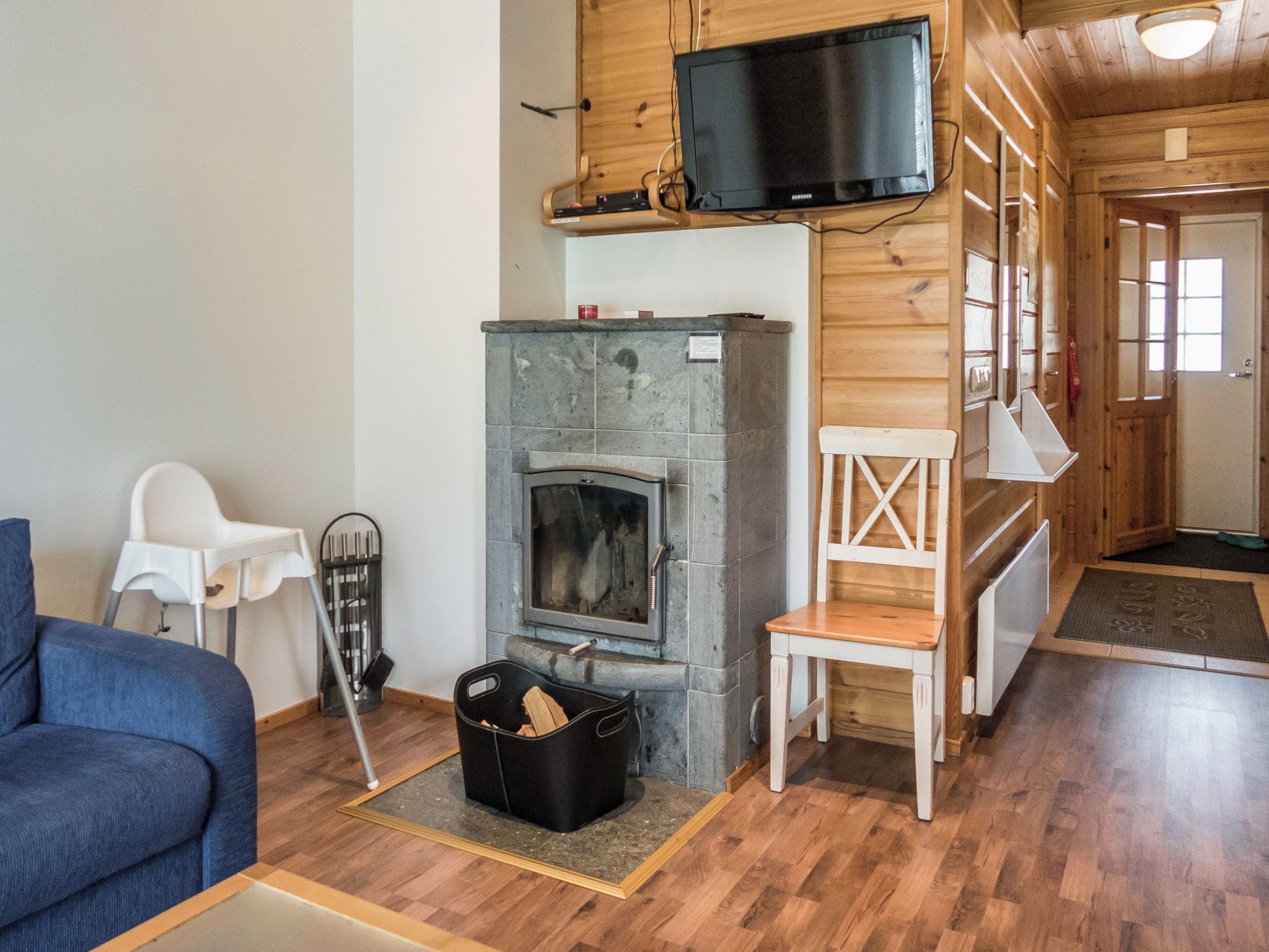 Una sala de estar acogedora con chimenea, un televisor montado encima y un sofá azul.