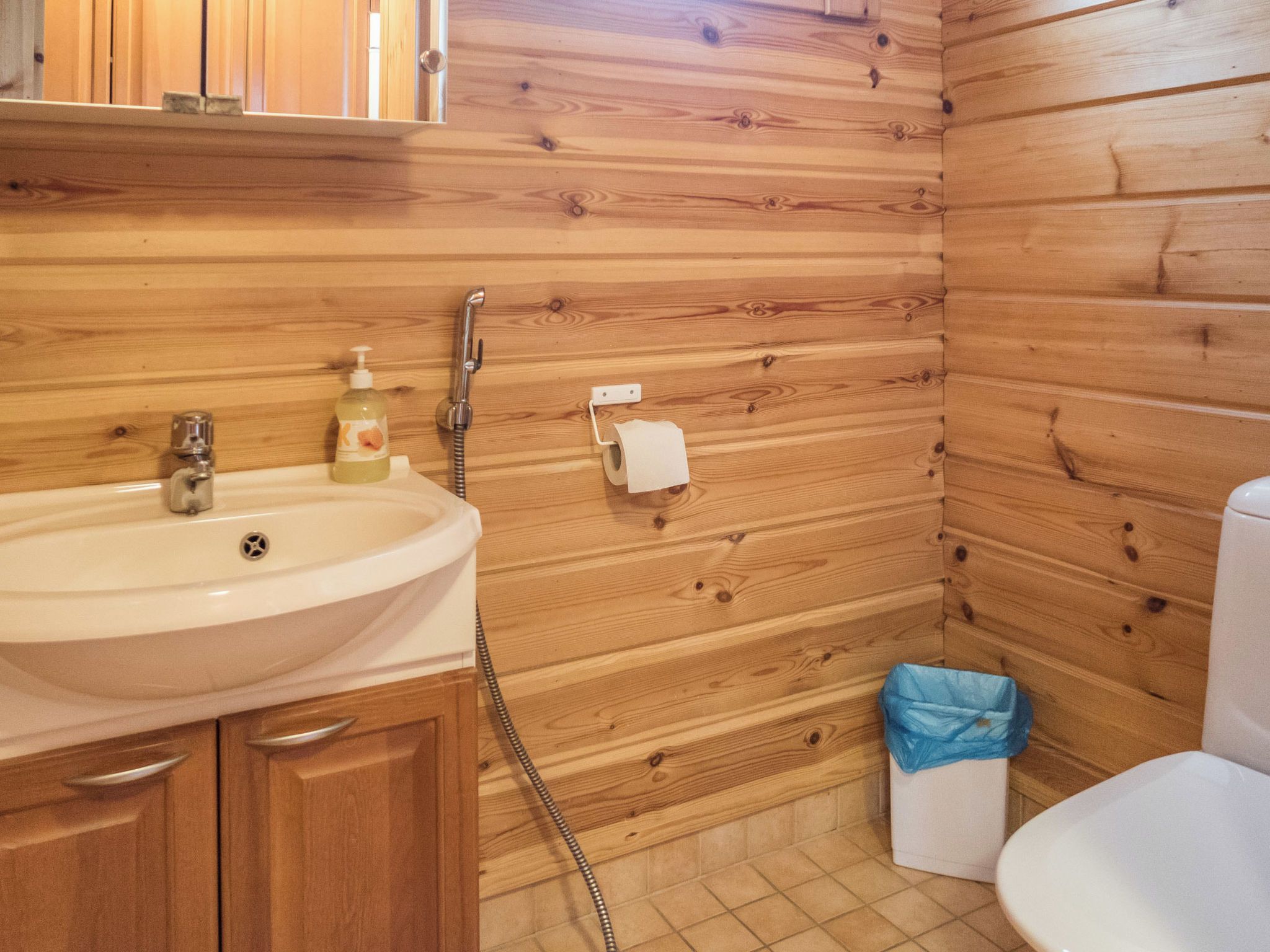 Une salle de bain aux murs lambrissés, équipée d’un lavabo, de toilettes et d’une douche.