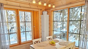 A wooden interior with large windows, a table with placemats, and a bowl of fruit. - Ihtingin koskikara by Interhome (Kuusamo)