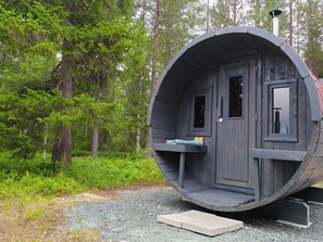 Een houten vakantiehuisje, cilindervormig, met een deur, ramen en een klein terras.