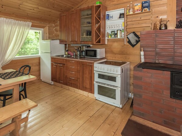 A compact kitchen with wooden cabinets, a microwave, a stove, and a refrigerator.