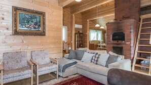 L’intérieur chaleureux d’un chalet en bois comprend un canapé, des fauteuils, une cheminée et un plafond en bois.