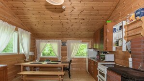 Une cuisine chaleureuse, aménagée dans le style d’un chalet, avec des murs en bois, une table en bois et un four en briques.
