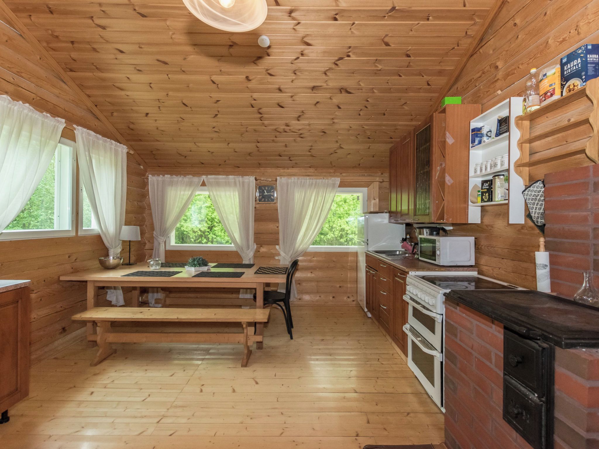 Interior de una cabaña de madera con cocina, comedor y chimenea.