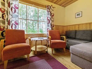 A cozy room with two armchairs, a sofa, a small table with a book, and a window with curtains.