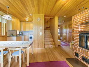 Un interior de madera con cocina, comedor y chimenea.