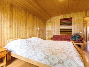 Una habitación de madera con una cama, un banco y un peluche.