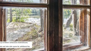 A window with a view of a natural landscape, including trees and a body of water.