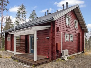 Une cabane en bois rouge, dotée d’un porche couvert, d’une cheminée et du numéro « 12 » sur la porte.