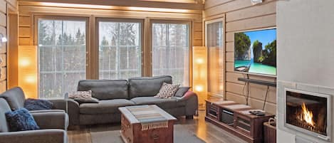 Una sala de estar acogedora con chimenea, un conjunto de sofás y un televisor.