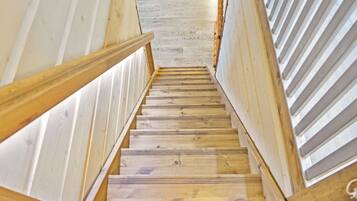 Una escalera de madera de diseño moderno que conduce a una habitación con piso de tonos claros.