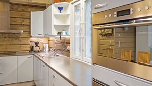 Una cuina moderna amb armaris blancs, una cuina d'acer inoxidable i un forn integrat.