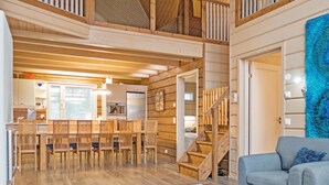 Un espaiós saló tipus loft amb taula i caires de dinar, una escala i una paret blava amb textura.